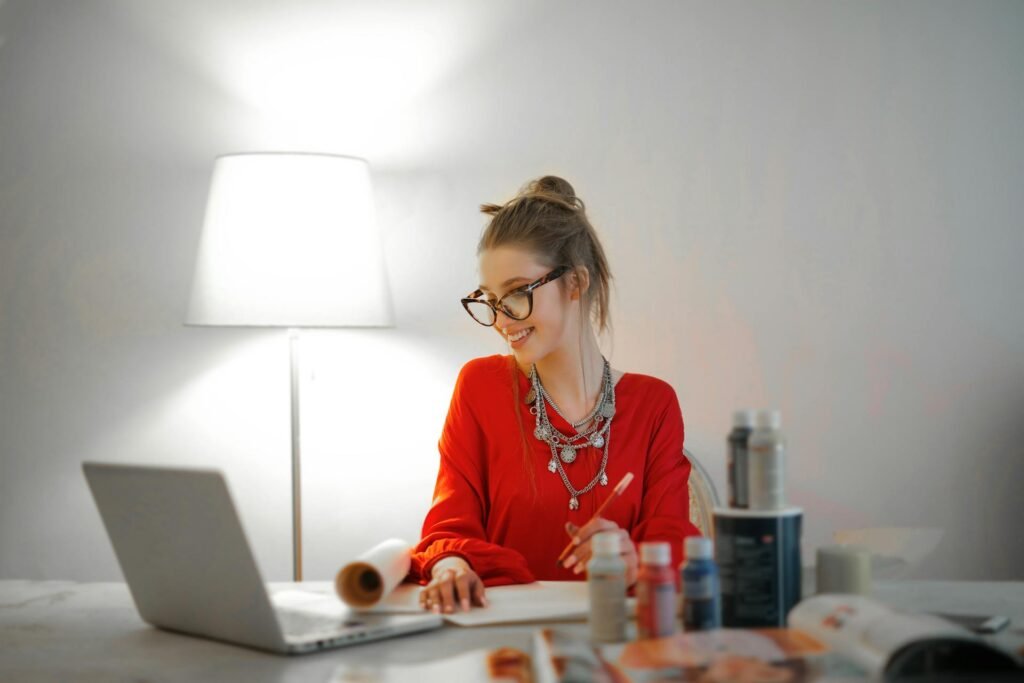 a female in orange sweater working on a computer in a happy mood